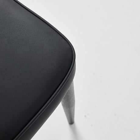 Close-up of a black restaurant chair with vinyl upholstery and gray legs, showcasing its sleek design and comfort.