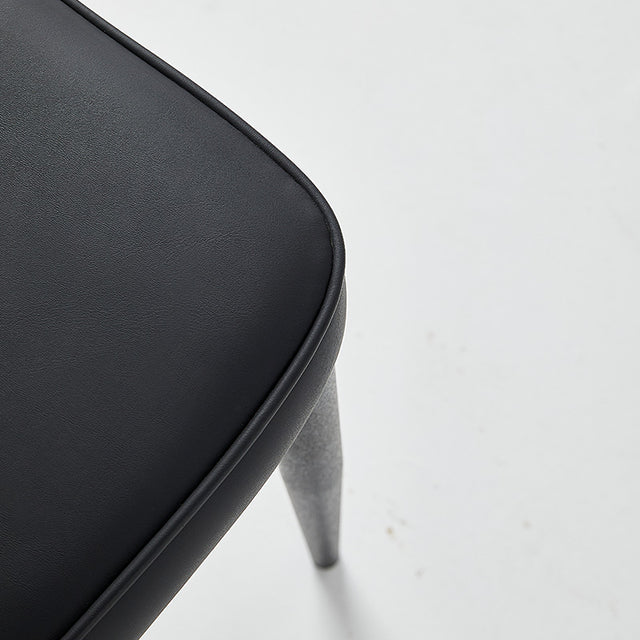 Close-up of a black restaurant chair with vinyl upholstery and gray legs, showcasing its sleek design and comfort.
