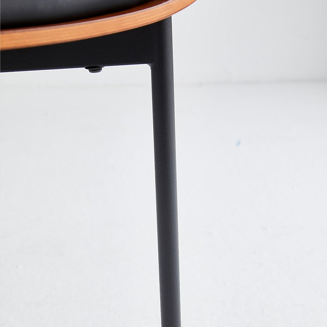 Close-up of black restaurant chair leg showcasing sturdy 18-gauge steel frame and scratch-resistant vinyl upholstery.