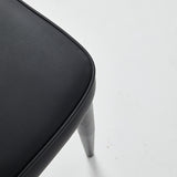 Close-up of a black restaurant chair with vinyl upholstery and gray legs, showcasing its sleek design and comfort.